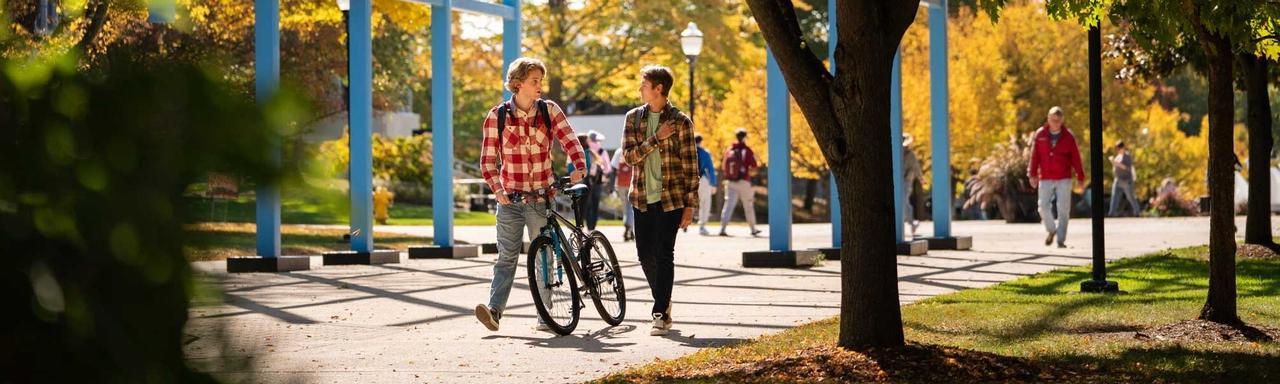 一名学生与另一名骑自行车的学生在转轨下步行